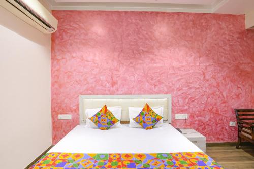 a bedroom with a bed with a pink wall at FabHotel Uday Villa in Kānpur