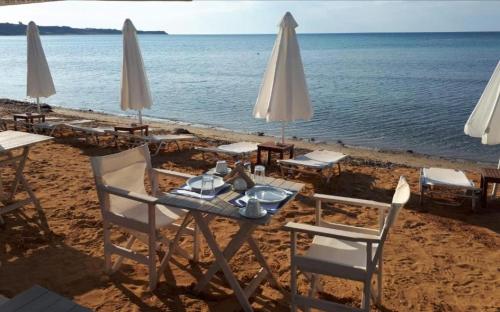 a table with chairs and umbrellas on a beach at Southbank seafront apartments in Katelios