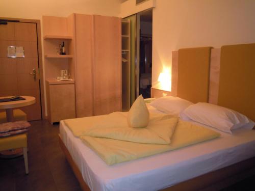 a bedroom with a bed with white sheets and pillows at Beach Hotel Du Lac Malcesine in Malcesine