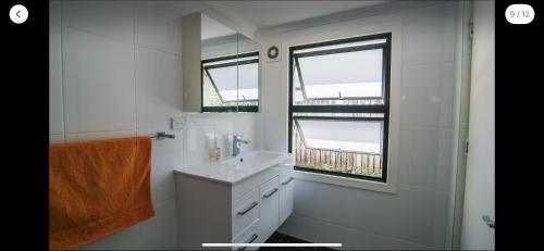 a white bathroom with a sink and two windows at Grimshaw House in Cairns
