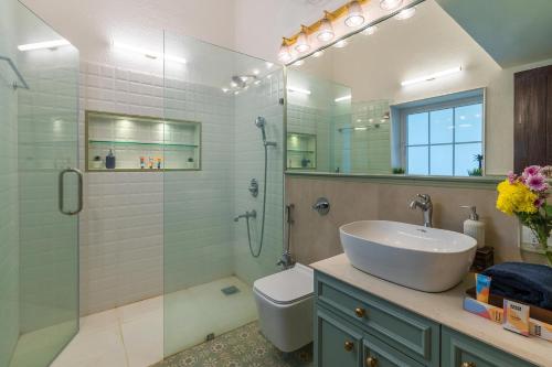 a bathroom with a sink and a toilet and a shower at The Beach House by StayVista with Modern interiors, nearby beach, pool, lawn in Alibaug