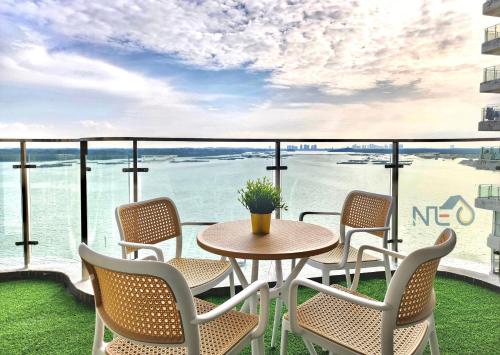 a table and chairs on a balcony with a view of the ocean at Country Garden Danga Bay InStyle Sea View Homestay Suite by NEO in Johor Bahru