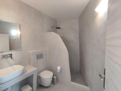 a white bathroom with a sink and a toilet at Central Santorini Serenity Rooms in Fira
