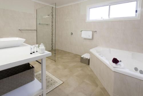 a white bathroom with a tub and a sink at Brookfield Guest House in Myrrhee