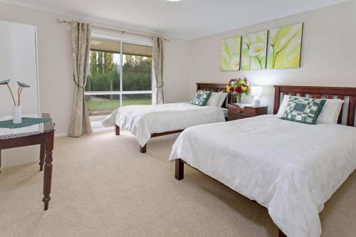 Un dormitorio con dos camas y un escritorio y una ventana. en Brookfield Guest House, en Myrrhee