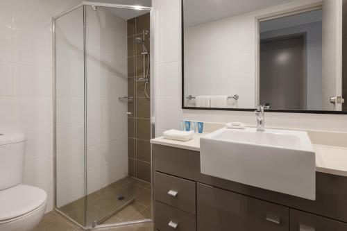a bathroom with a sink and a toilet and a mirror at Meriton Suites Broadbeach in Gold Coast