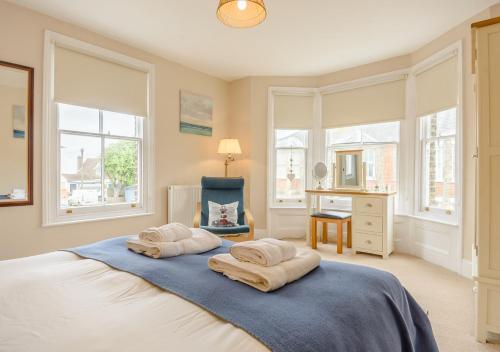 a bedroom with a bed and a chair and windows at Salisbury House in Southwold