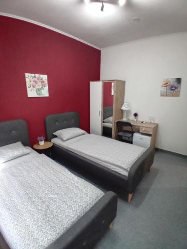 a room with two beds and a red wall at Pansion San in Bihać