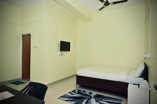 Habitación pequeña con cama y escritorio. en Queen's Residency en Guwahati