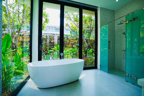 a large bathroom with a tub and a glass shower at Kiwuki Beachfront Villa in Phu Quoc