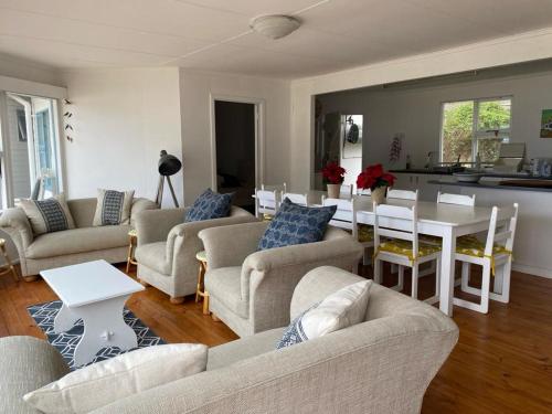 a living room with couches and a table and a kitchen at MakiSaki Beach House in Herolds Bay