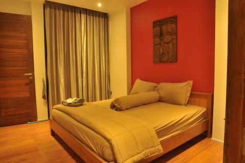 a bedroom with a bed with a red wall at Pony Hill Villa in Bophut