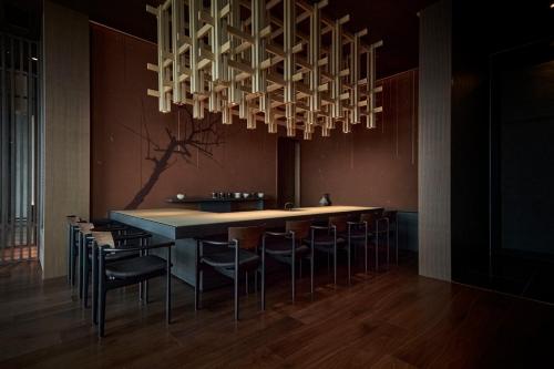 a dining room with a table and chairs under a chandelier at The Royal Park Hotel Iconic Nagoya in Nagoya