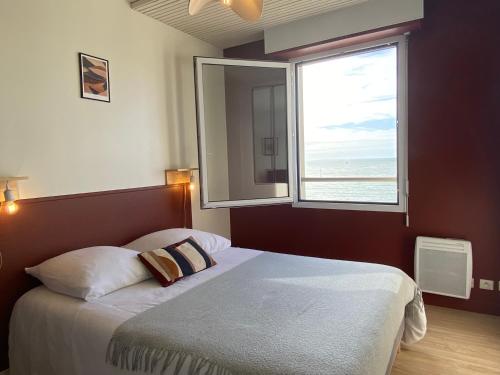 een slaapkamer met een bed en een groot raam bij Front de mer vue exceptionnelle in Granville