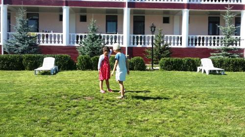 two people standing in the grass in front of a house at Aquamarine Inn in Cholpon-Ata
