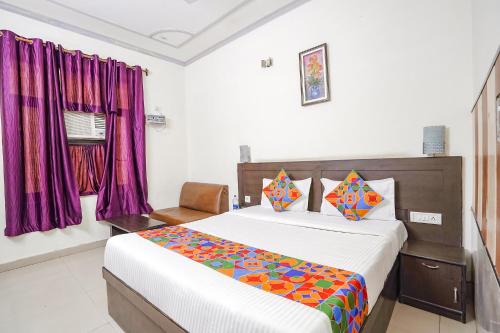 a bedroom with a bed and purple curtains at FabHotel Prashant Palace in Agra