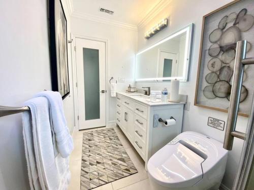 Baño blanco con aseo y lavamanos en Luxury White Beach House en Redondo Beach