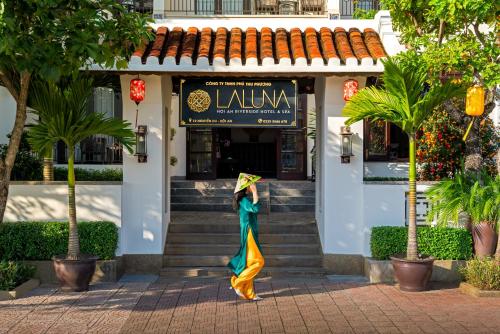 Una donna che cammina davanti a un palazzo di Laluna Hoi An Riverside Hotel & Spa a Hoi An