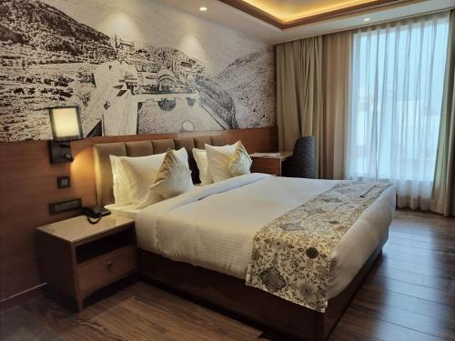 ein Hotelzimmer mit einem großen Bett und einem Wandbild in der Unterkunft Hotel Royal Lakshmi Palace in Jaipur