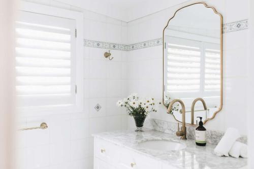 een witte badkamer met een wastafel en een spiegel bij Coromandel Cottage, Berrima in Berrima