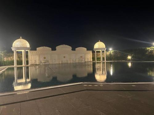 ein Gebäude mit zwei Kuppeln im Wasser in der Nacht in der Unterkunft Celestial Chic Suite With Swimming Pool in Lucknow