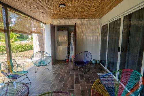 a screened porch with chairs and a refrigerator at Villa Paraiso do Mar in Jacó