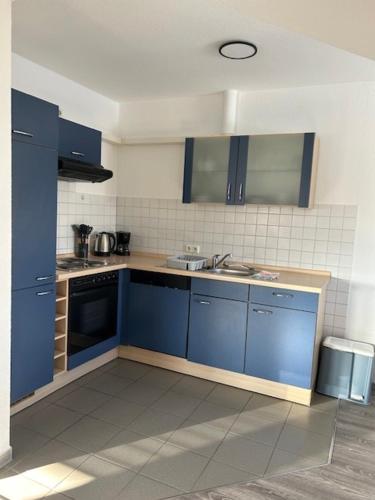 eine Küche mit blauen Schränken und einem Waschbecken in der Unterkunft Appartement 6 in Hilter in Hilter am Teutoburger Wald