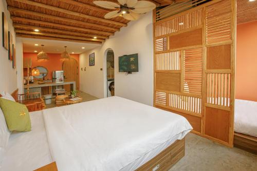 a bedroom with a large white bed and a kitchen at TA Danang Boutique Hotel in Da Nang