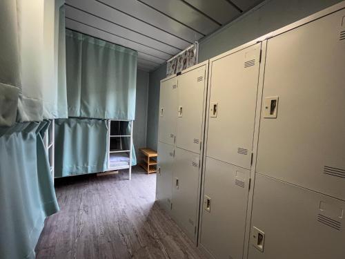 鉄木彩虹小屋 في Yü-lan: غرفة خزانة مع خزانات بيضاء وستارة زرقاء