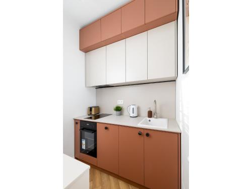 a kitchen with brown and white cabinets and a sink at ECRU Design Apartment in City Center WWA46 in Warsaw