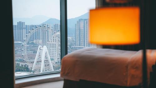 a bedroom with a view of a city from a window at DoubleTree By Hilton Ningbo Beilun in Ningbo