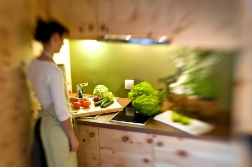 a woman standing in a kitchen with vegetables on a counter at Ansitz Velseck-Residence Hotel in Tires