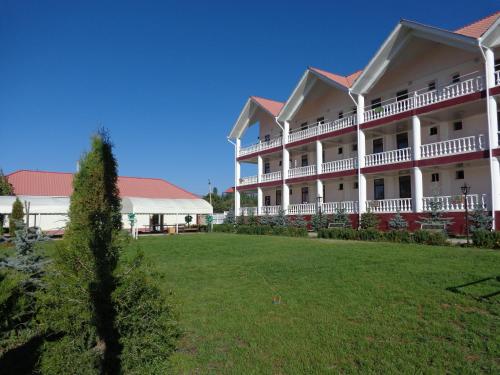 a large white building with a green yard at Aquamarine Inn in Cholpon-Ata
