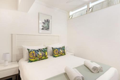 a white bedroom with a bed and a desk at Clifton Studio 104 in Cape Town