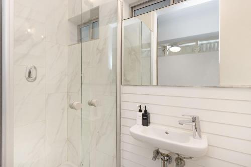 a white bathroom with a sink and a shower at Clifton Studio 104 in Cape Town