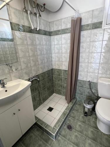 een badkamer met een douche, een wastafel en een toilet bij Rooftop Apartment in Larisa