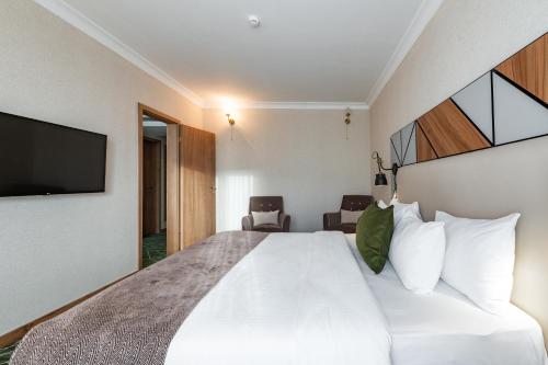 a bedroom with a large white bed and a flat screen tv at Wyndham Garden Burabay in Borovoye