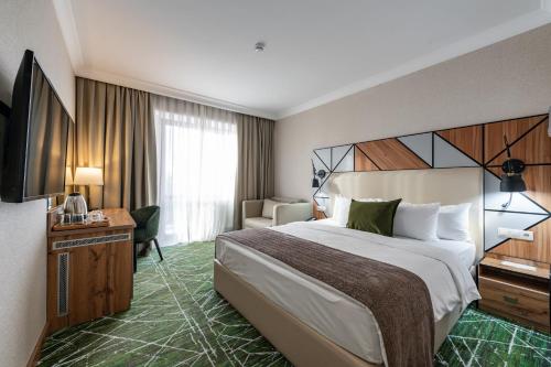 una camera d'albergo con un grande letto e una TV di Wyndham Garden Burabay a Borovoye