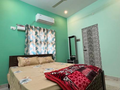 a bedroom with a bed with green walls at Sai Ayush Homestay in Kumbakonam