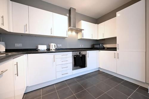 a white kitchen with white cabinets and appliances at London Apartment Next To Station + Parking in Beckenham