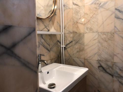een witte wastafel in een badkamer met marmeren muren bij T2 ultracentre au calme Animaux acceptés in Arcachon