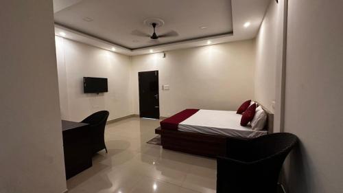 a bedroom with a bed and a desk and a tv at Long Acres in Guwahati
