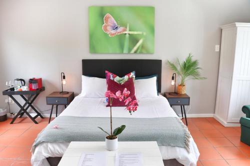 een slaapkamer met een bed met een vlinderschilderij aan de muur bij Island Villa in Knysna