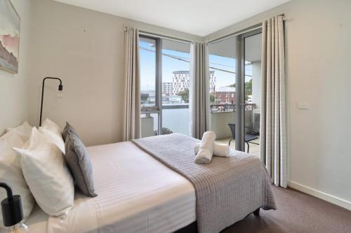 a bedroom with a large bed with a balcony at Terminus Apartment I Steps from Geelongs Buzz in Geelong