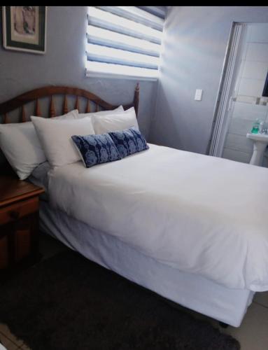 a large white bed with a blue pillow on it at Nasrec Guesthouse in Johannesburg