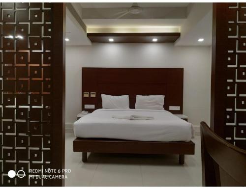 a bedroom with a large bed with white sheets at Hotel Maurya International, Chennai in Chennai