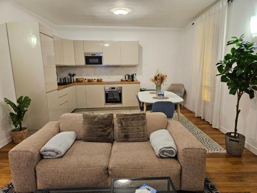 een woonkamer met een bank en een tafel bij Somptueux appartement proche stade de france in Enghien-les-Bains