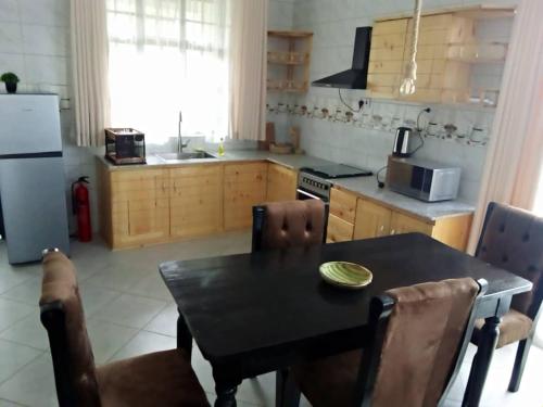 eine Küche mit einem Esstisch und einem Kühlschrank in der Unterkunft FABRISSA HOMES in Arusha