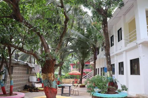 einen Innenhof mit Bäumen, einem Tisch und Stühlen in der Unterkunft Vellankani Resort Gorai in Mumbai
