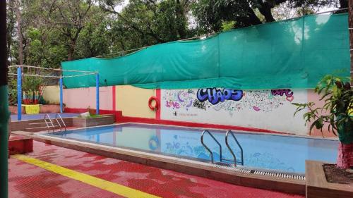 een groot zwembad met een groen dak bij Vellankani Resort Gorai in Mumbai